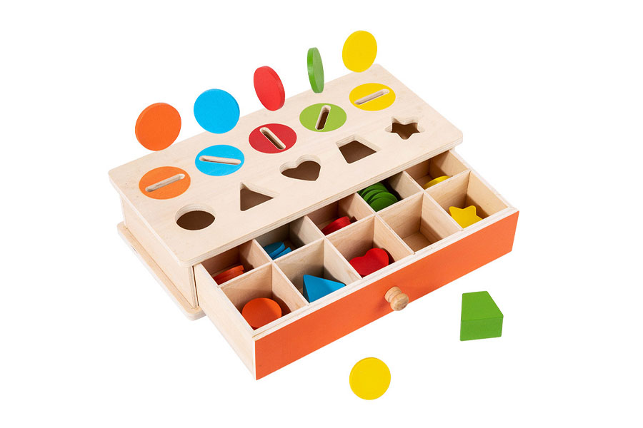 A child in a classroom setting using wooden beads for a threading activity
