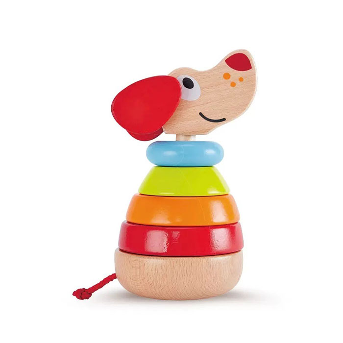 A happy 1-year-old baby sitting on the floor, playing with a colorful wooden ring stacker.