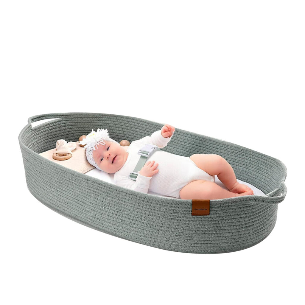 A peaceful parent on a sofa with their newborn sleeping safely in a Moses basket beside them