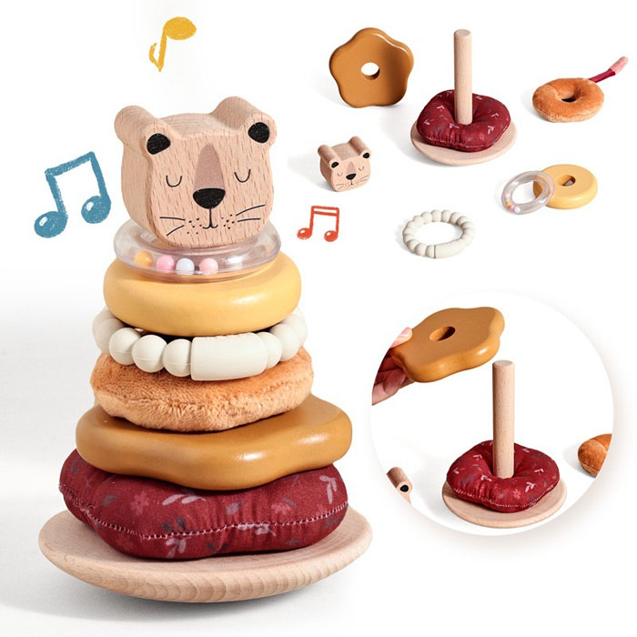 A 1-year-old successfully placing a ring on a stacking toy, with a shape sorter in the background.