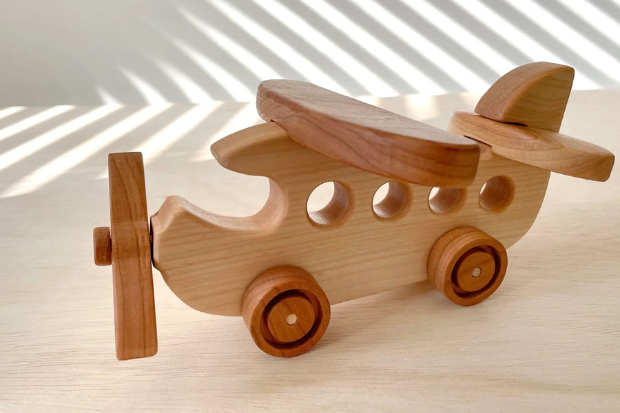 A child dropping a wooden plane and watching it fall to understand gravity