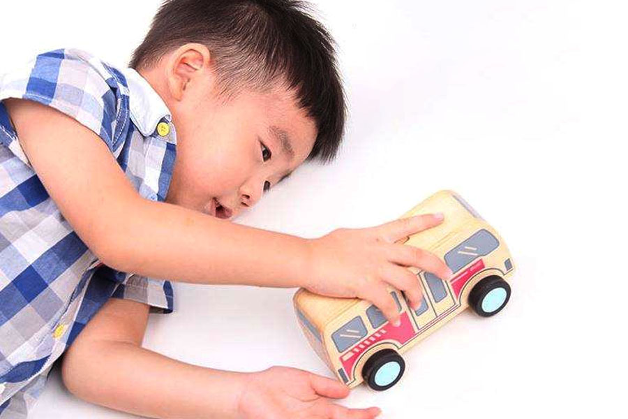 A child experimenting with a wooden car on ramps of different heights.