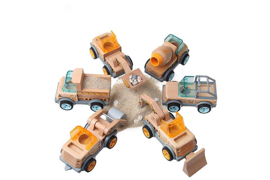 A child making 'vroom' sounds while pushing a simple wooden car through a city made of blocks.