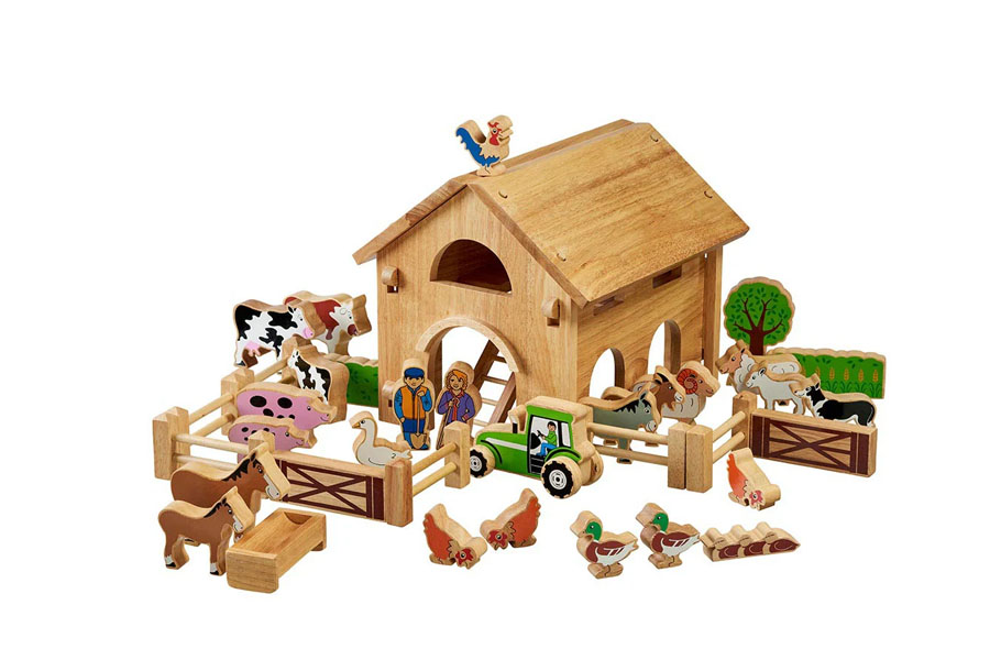 A classic, beautifully made wooden toy barn with open doors and a few animal figures nearby