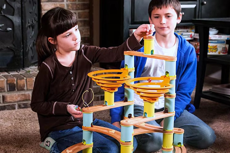 A close-up shot of a child's hands carefully placing one wooden block atop another.