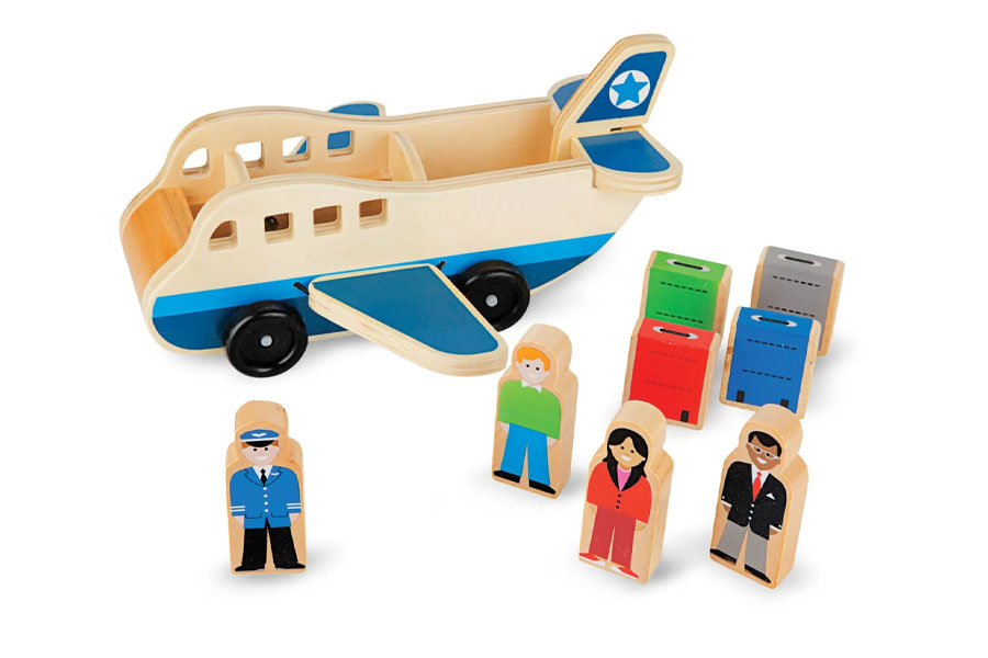 A toddler carefully holding a wooden plane, focusing on its details