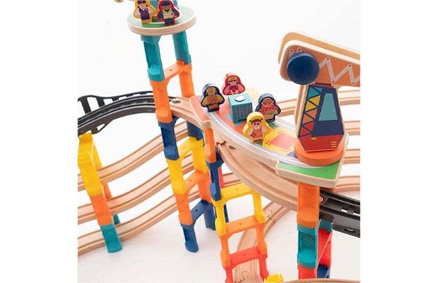 A wooden train stopped at a small wooden station, with peg dolls as passengers.