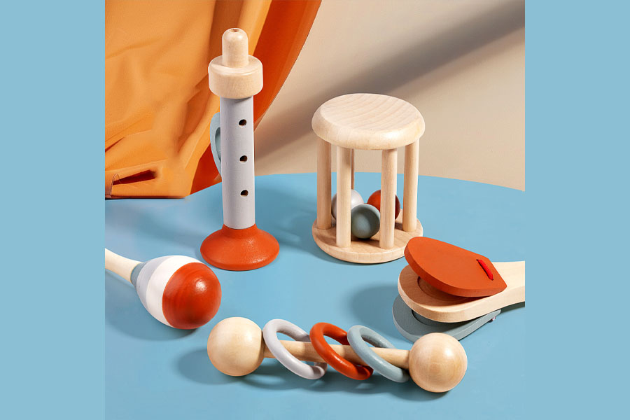 An infant's tiny hand closing around a simple wooden grasping ring